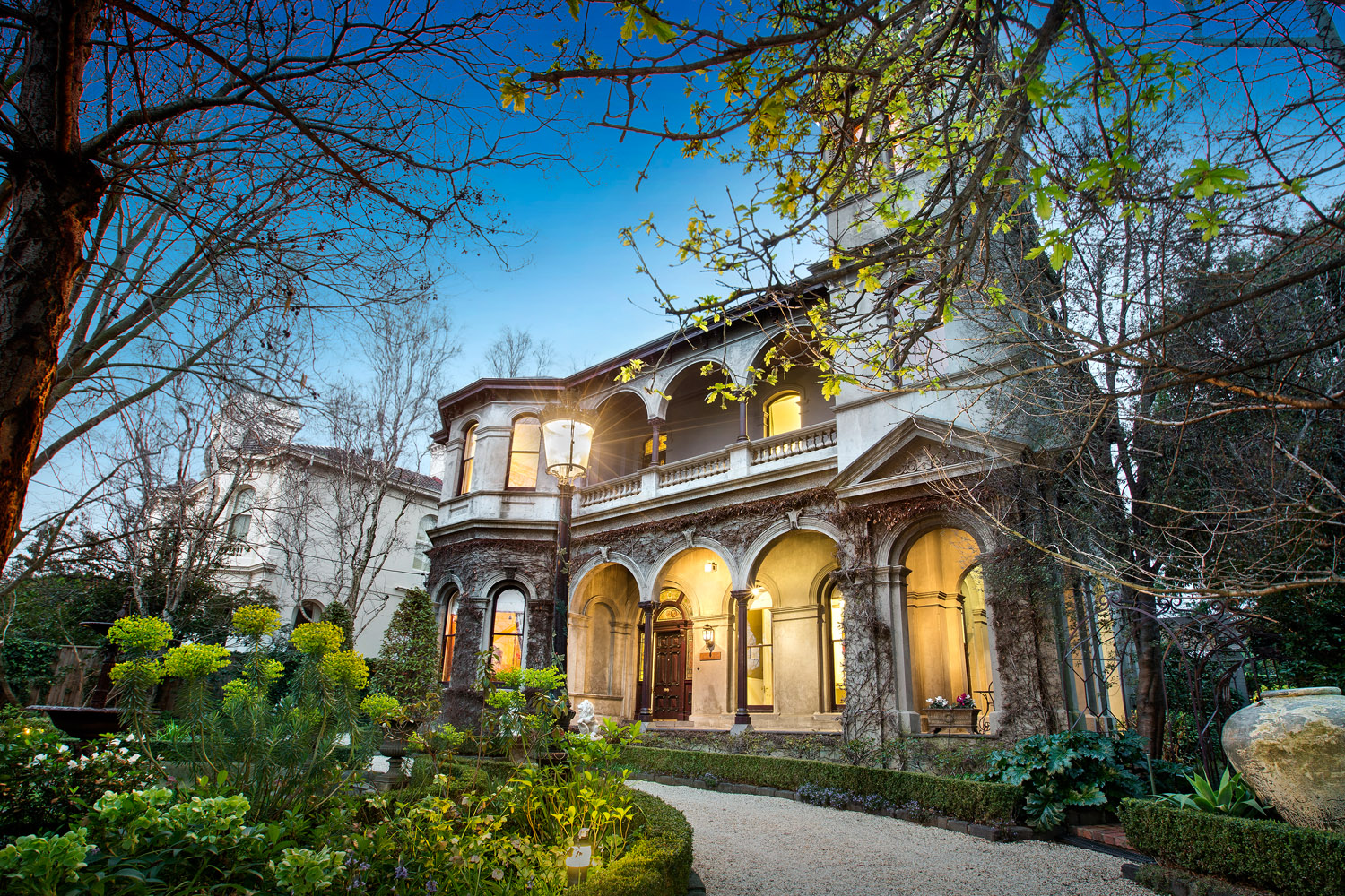 Victorian-style house in Melbourne with arched windows and balconies, set against a twilight sky.
