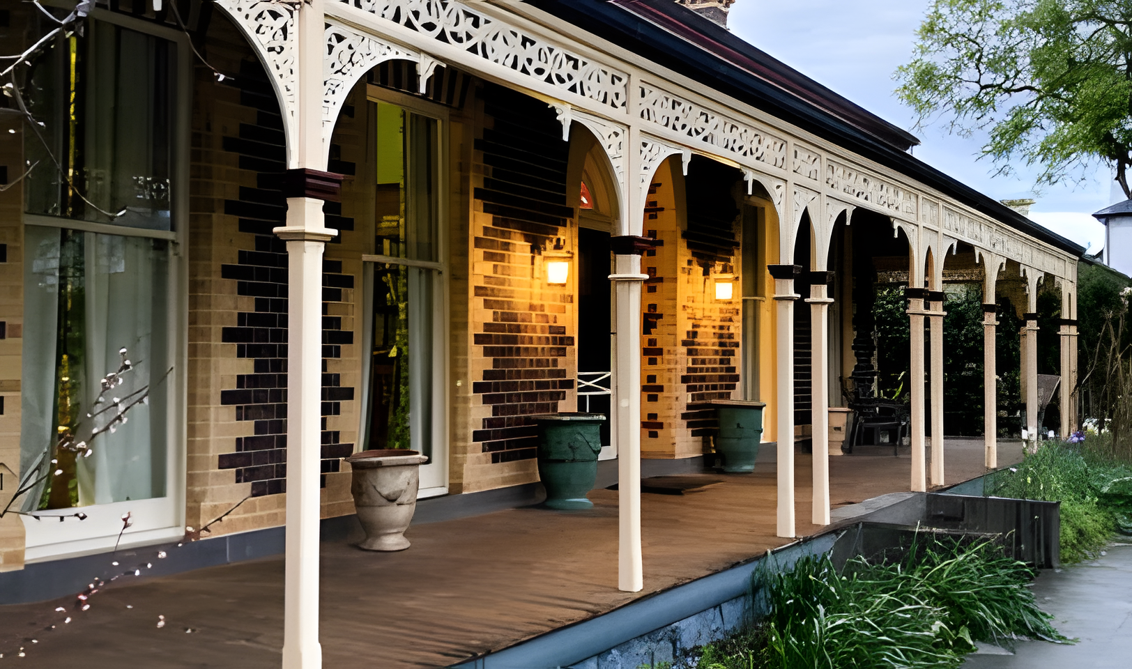 Victorian-style house with a fresh coat of paint on the walls, arches, pillars, and a wooden porch.