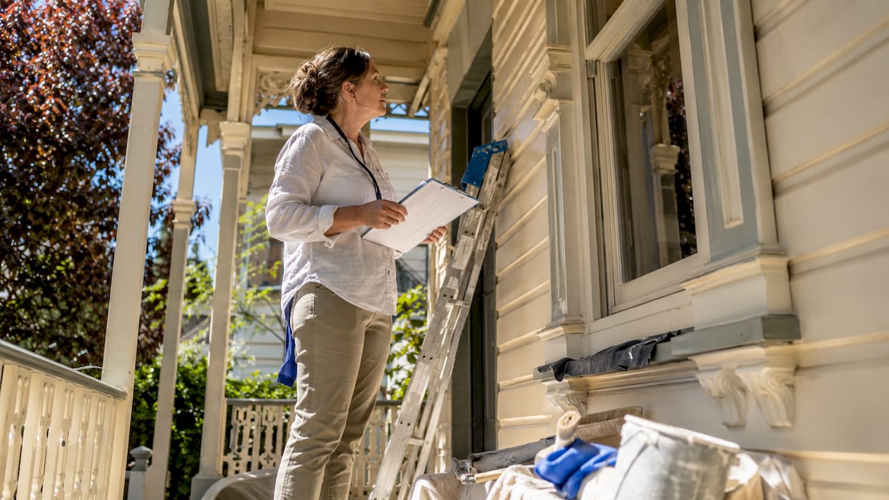 Homeowner reviewing painting checklist outside period home