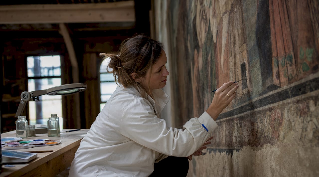 Art conservator restoring historic mural