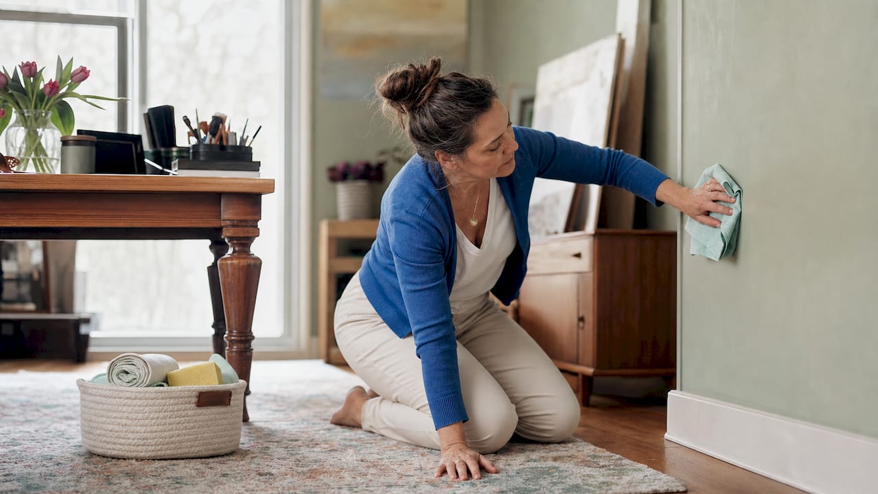 Woman cleaning painted wall with cloth