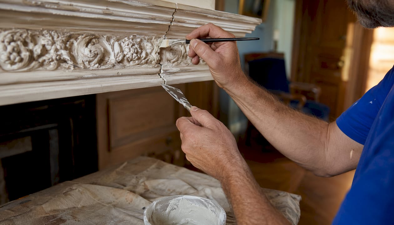 Hands repairing plaster cornice in heritage home