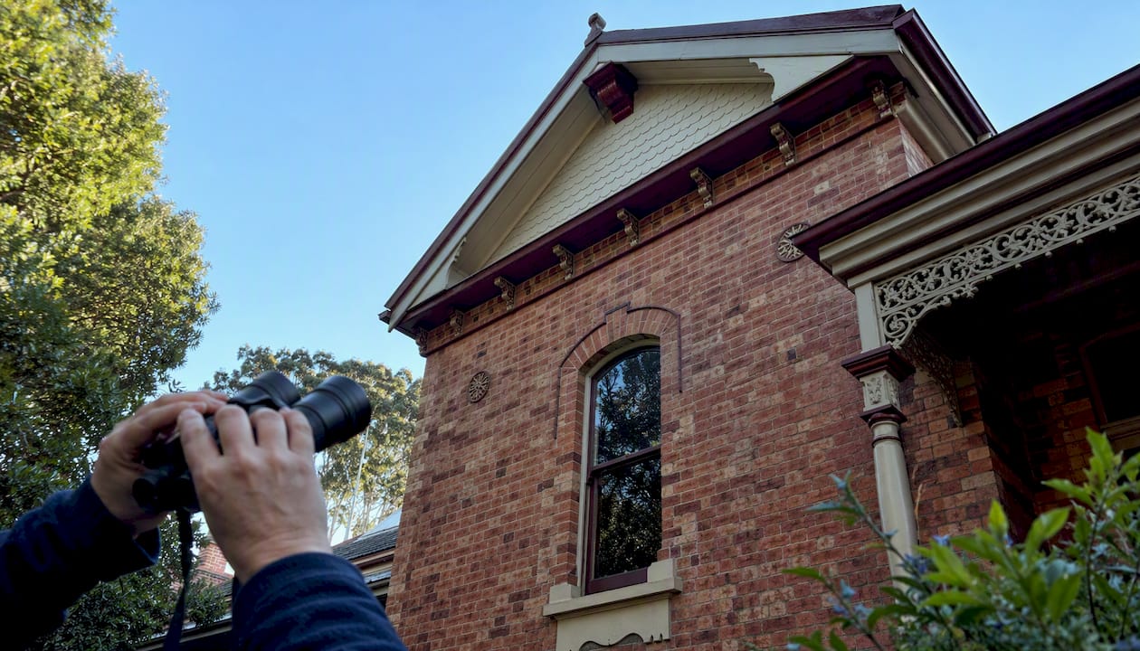 Binoculars aimed at upper brick facade