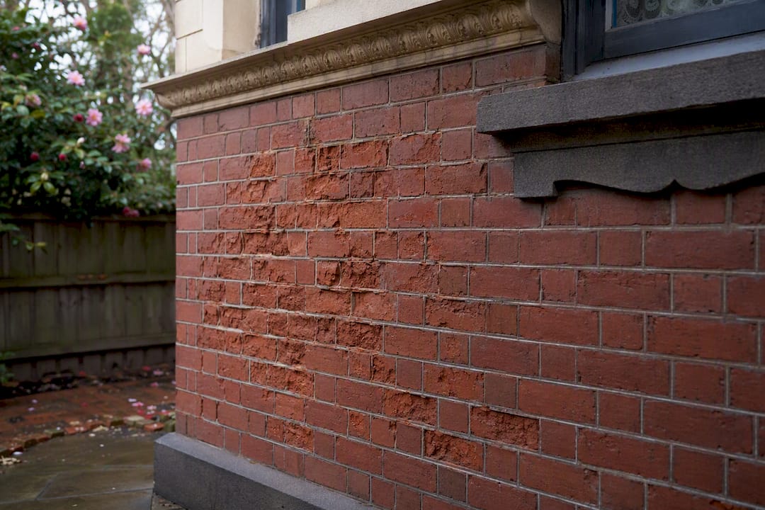 Damaged brick spalling from cement mortar on heritage wall