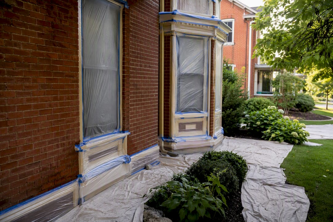 Plastic sheeting masking windows and garden beds