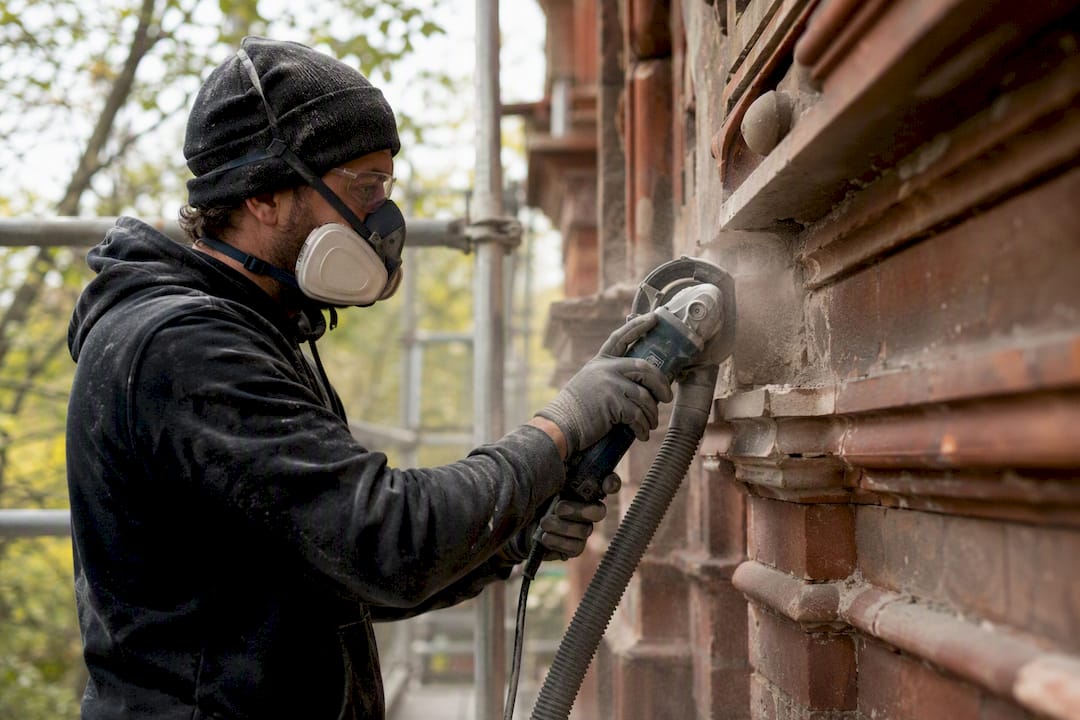 Worker cutting mortar wearing respirator and safety gear