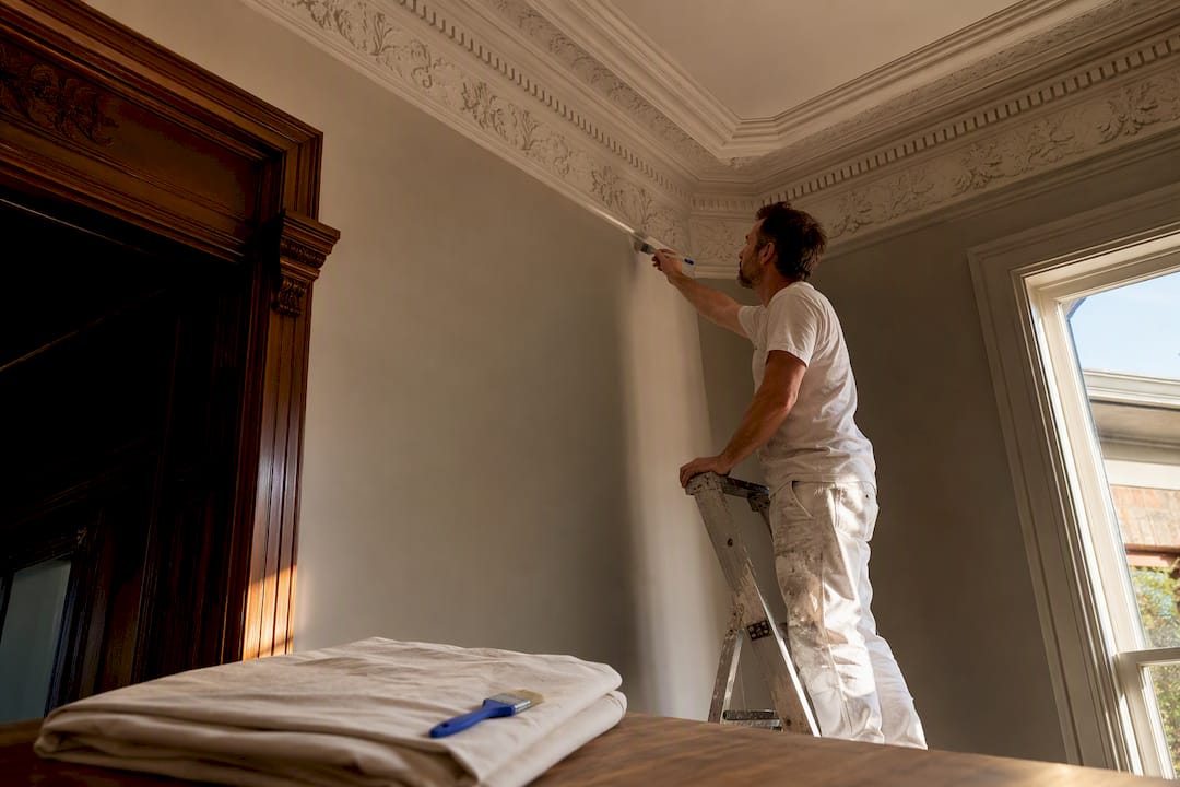 Painter preparing ornate Victorian interior cornice