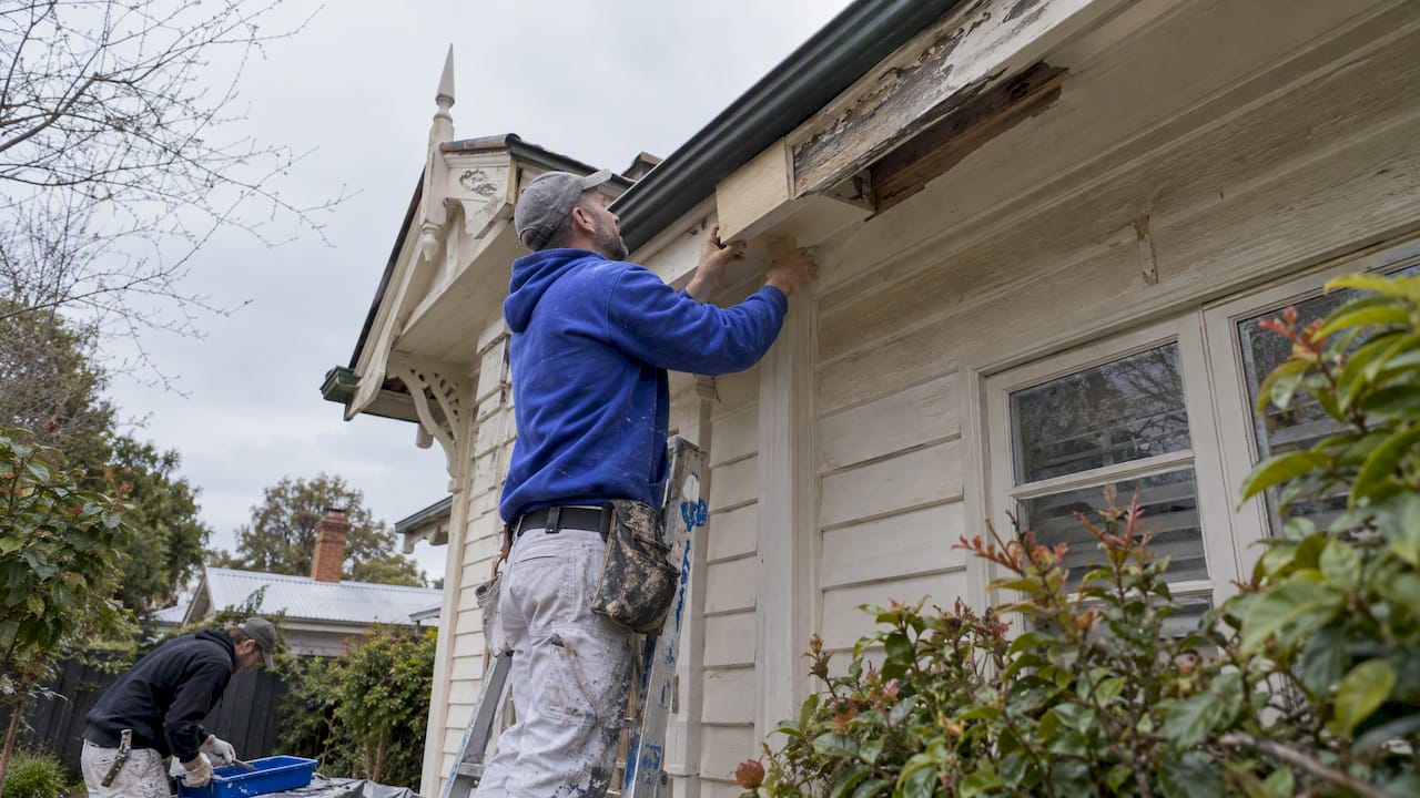 Painter repairing and priming Edwardian eaves